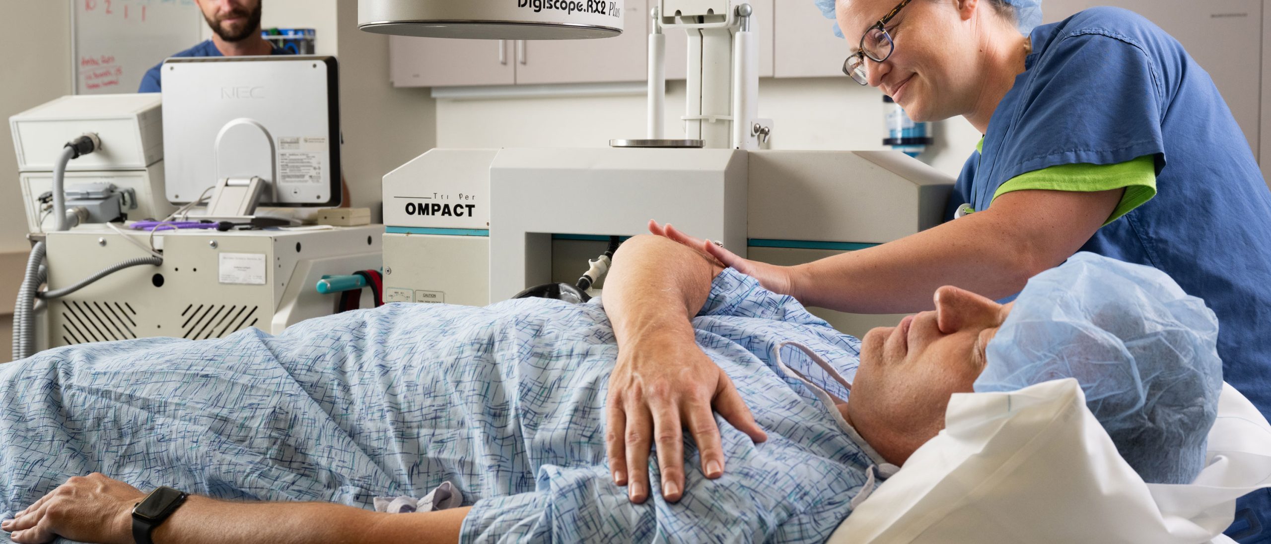 Patient lying on bed with people in scrubs caring for him