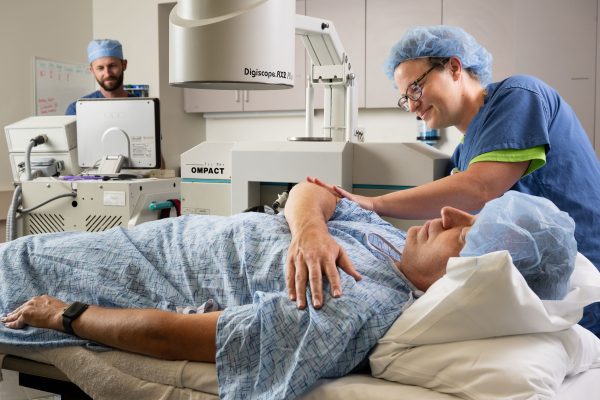 Patient lying on bed with people in scrubs caring for him