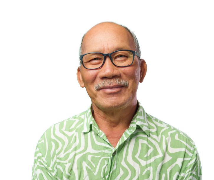 Older man with glasses soft smiling looking straight ahead with a green printed shirt