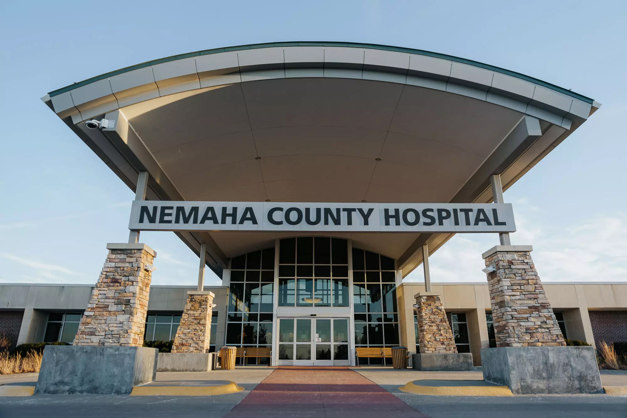 Main entrance of Nemaha County Hospital with stone columns and an awning. Many windows on the front in Auburn, Nebraska.