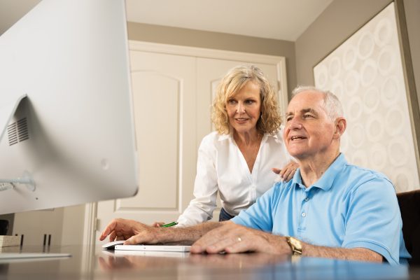 Man and woman sitting at a desk looking at a computer together